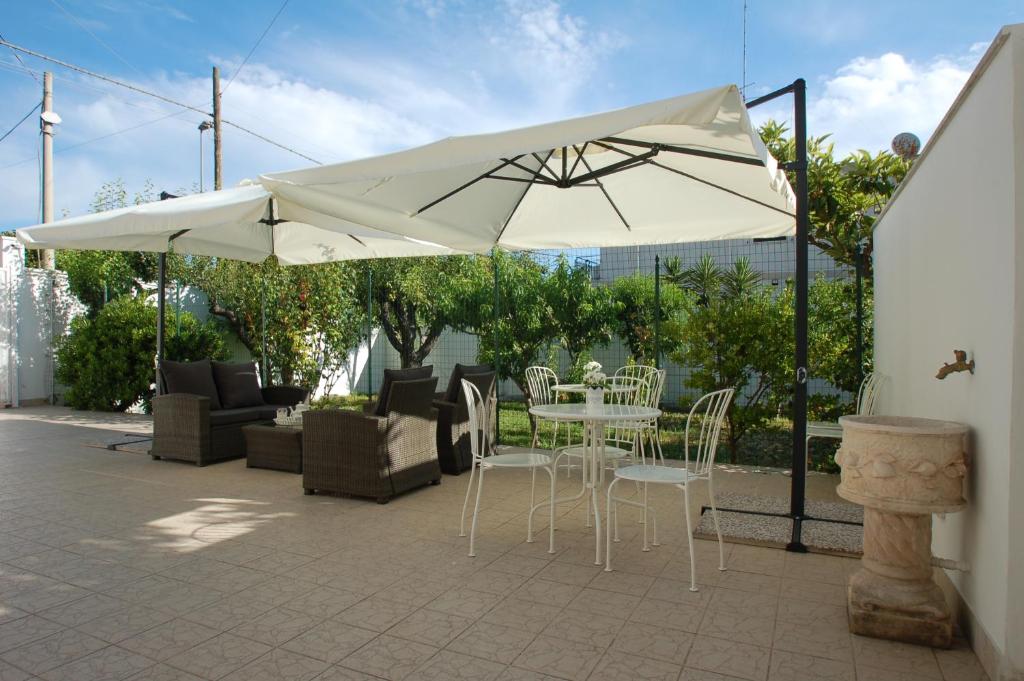 un patio con sombrilla, mesa y sillas en Giardino dei Frutti, en Bari