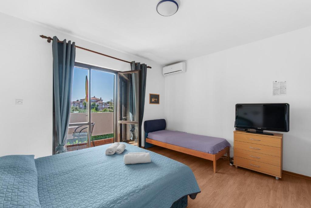 Schlafzimmer mit einem Bett und einem Flachbild-TV in der Unterkunft Apartments Villa Falcon in Funtana