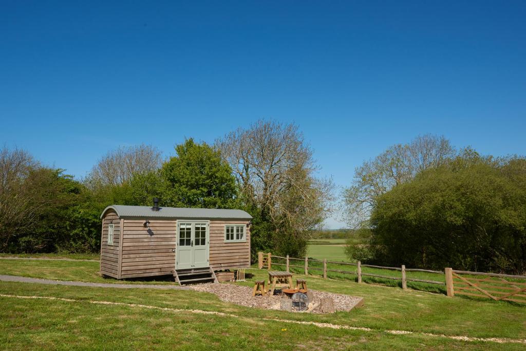 a small shed in the middle of a field at Foot of the Downs Shepherds Hut in Woodmancote