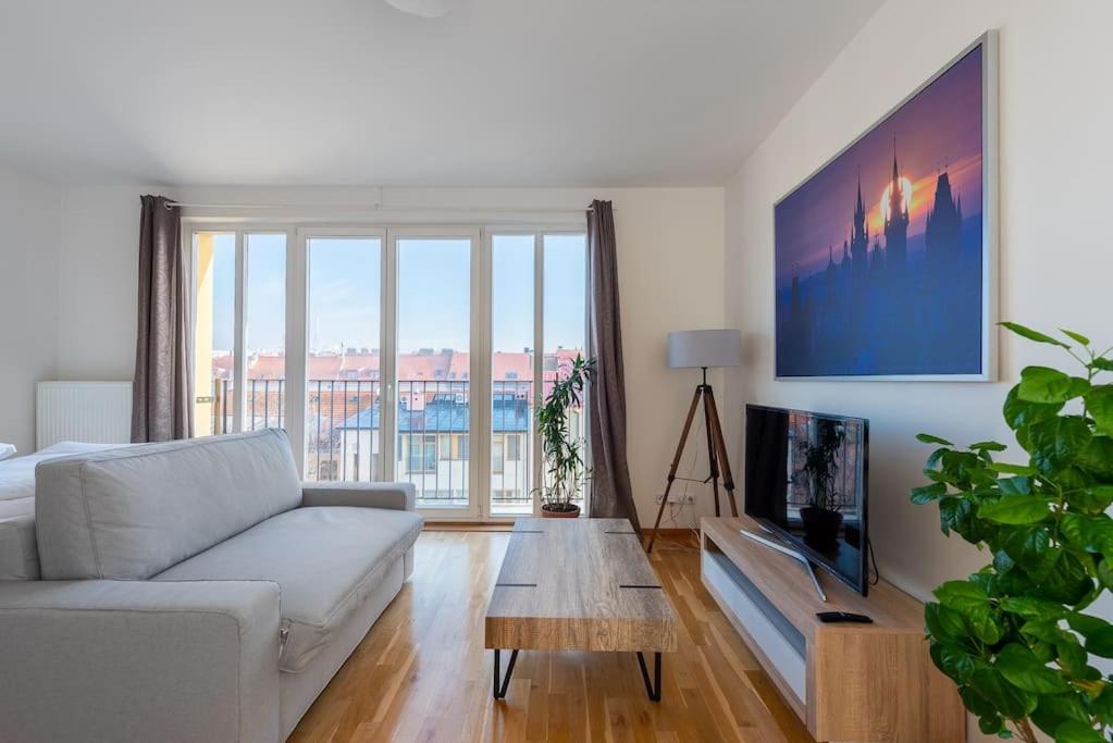uma sala de estar com um sofá branco e uma televisão em Sunny Safron apartment em Praga