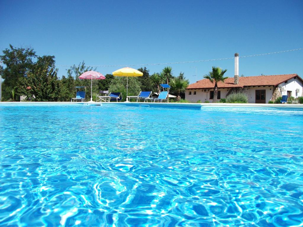 a large swimming pool with chairs and umbrellas at Agriturismo Rocce Bianche in Arbus