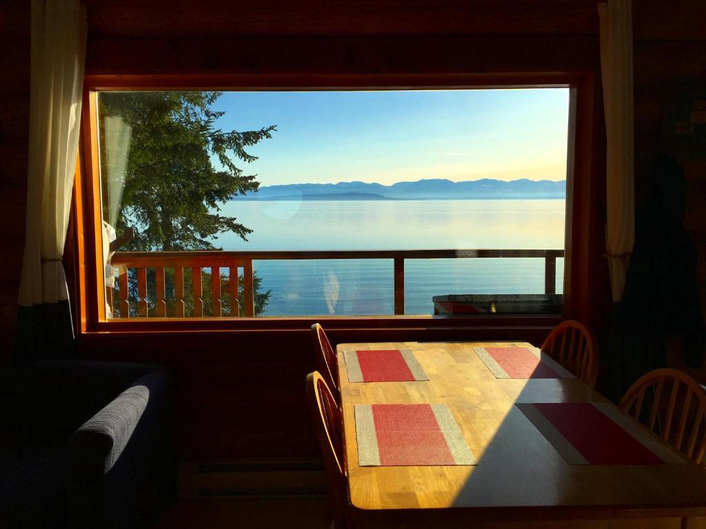 a table with a view of the water from a window at The Beach House Texada - Waterfront Cabin in Gillies Bay