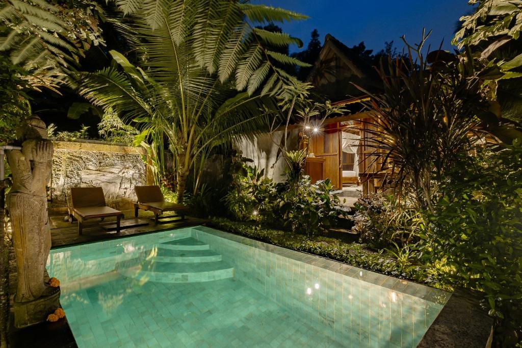 uma piscina no meio de um jardim em Moringa Ubud Villa em Ubud