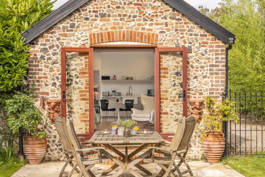 a brick shed with a table and chairs in front of it at Weavers Mark Cottage in Diss