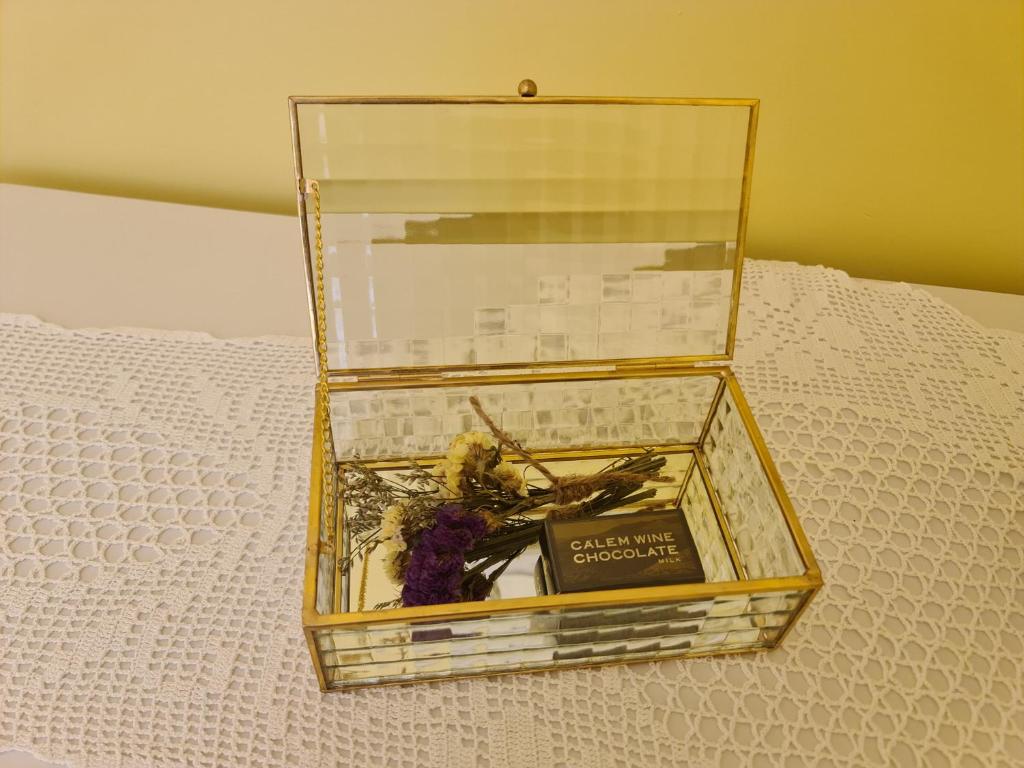 Una caja de cristal con un libro y flores. en Casinhas no Carolina - Hostel en Oporto