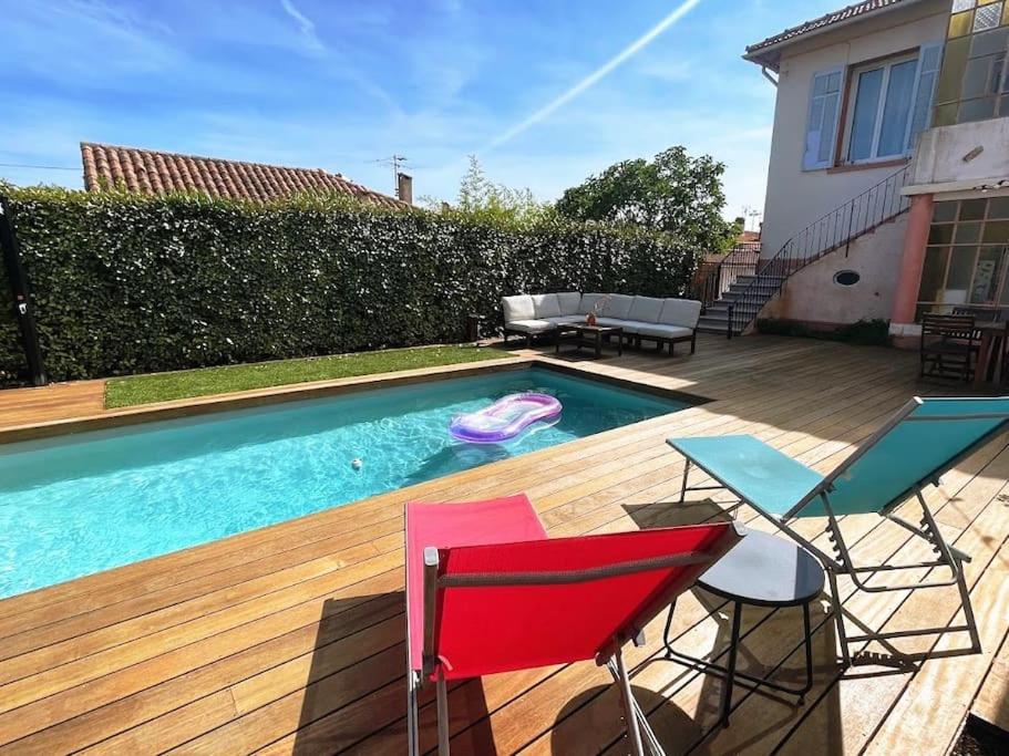 a backyard with a swimming pool and chairs and a house at Studio rez-de-villa - Parking facile - Proche gare in Toulon