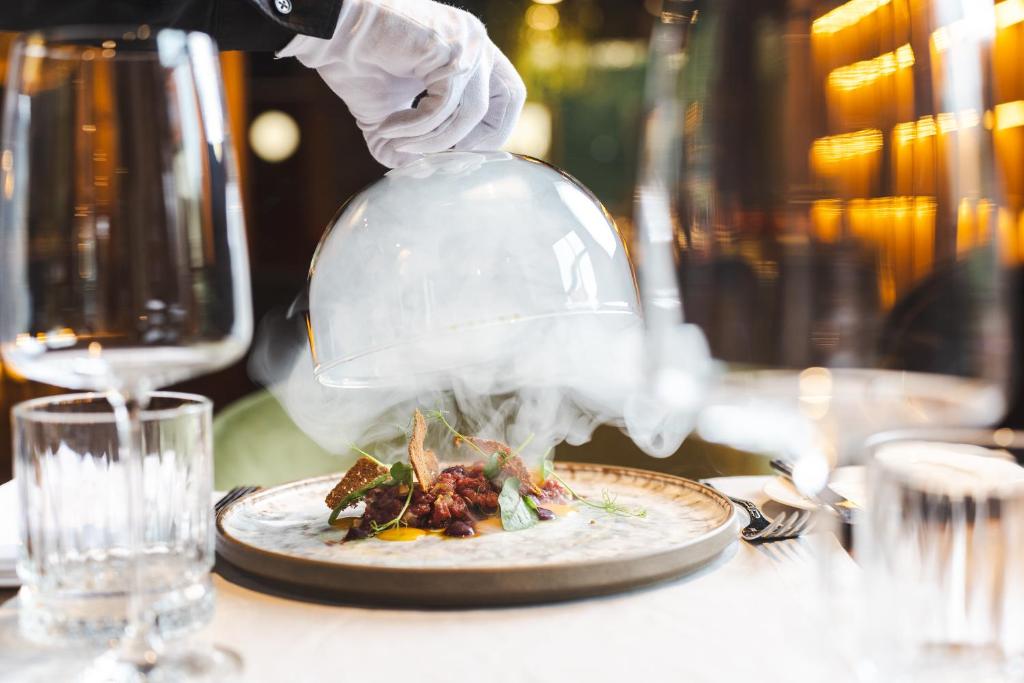 a plate of food on a table with a chefs hat and a plate of food at Haffner Hotel & SPA Sopot - Destigo Hotels in Sopot