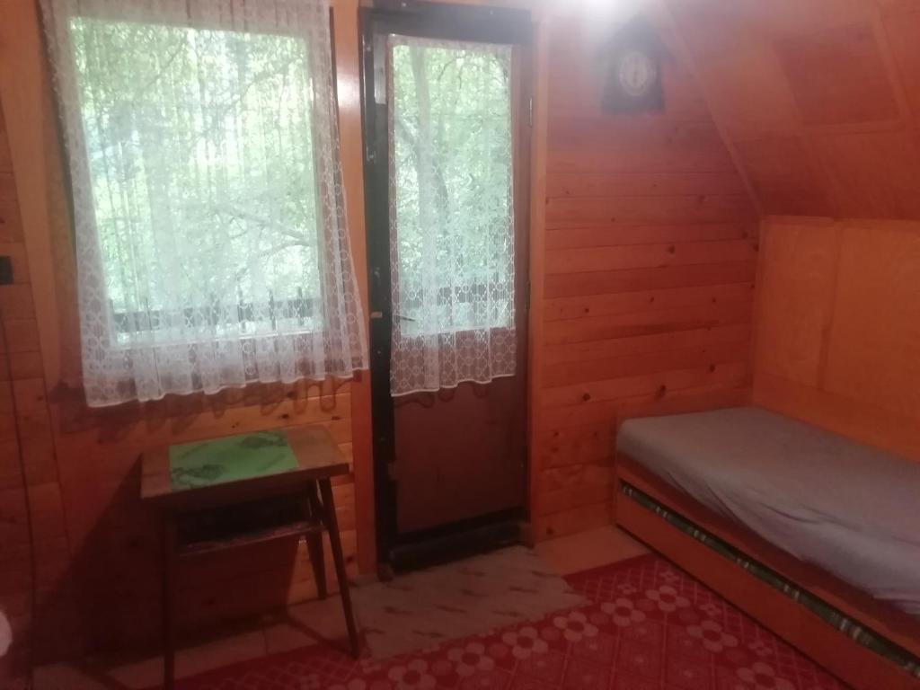 a small room with a bed and two windows at Chata Lužná u Hanušovic 
