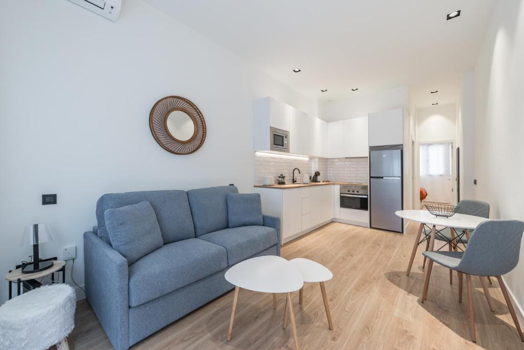 uma sala de estar com um sofá azul e uma cozinha em JES Apartment A Nuevos Ministerios em Madri