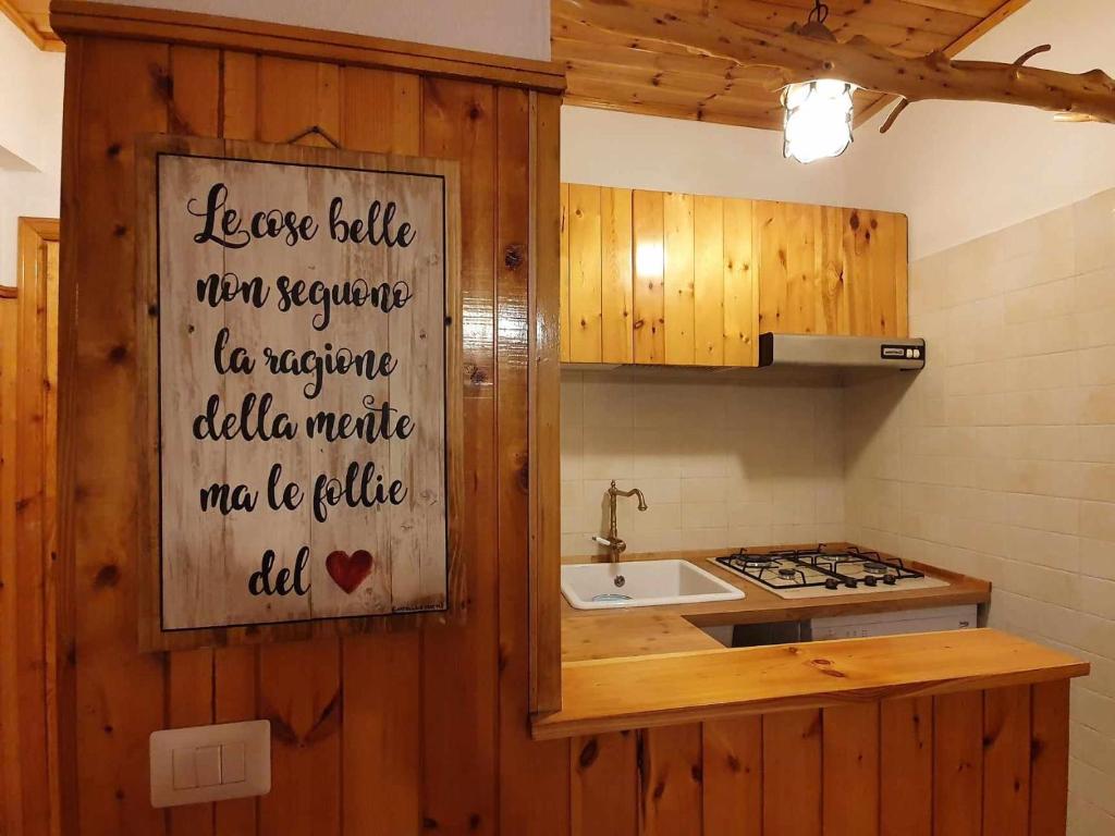 uma cozinha com um lavatório e uma placa na parede em La Piccola Baita di Filettino em Filettino