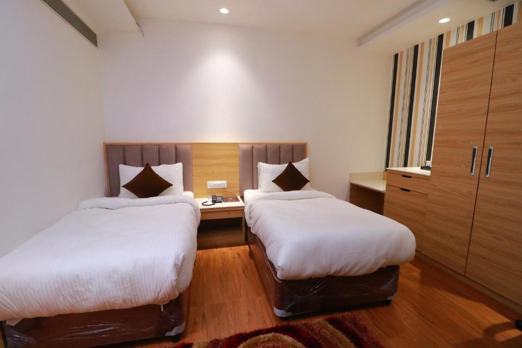 a hotel room with two beds and a desk at Country Green Hotel & Banquet in Bareilly