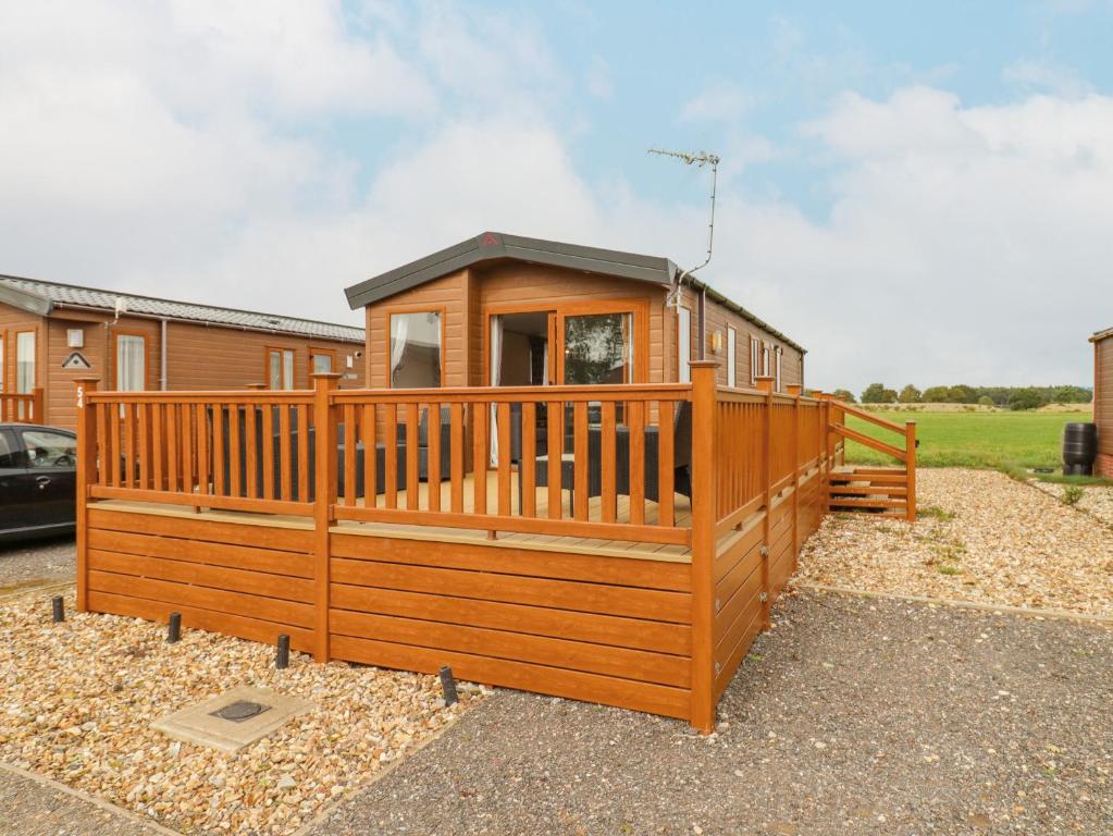 a large wooden cabin with a large deck at Number 54 in Stowmarket