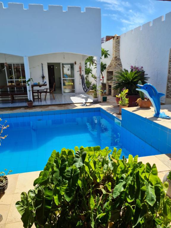 une piscine bleue avec des plantes dans une cour dans l'établissement Casa com piscina 300 M Broadway Canoa quebrada, à Canoa Quebrada