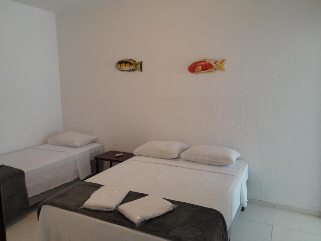 a room with two beds and a table and fish on the wall at Recanto do Centro in Cananéia