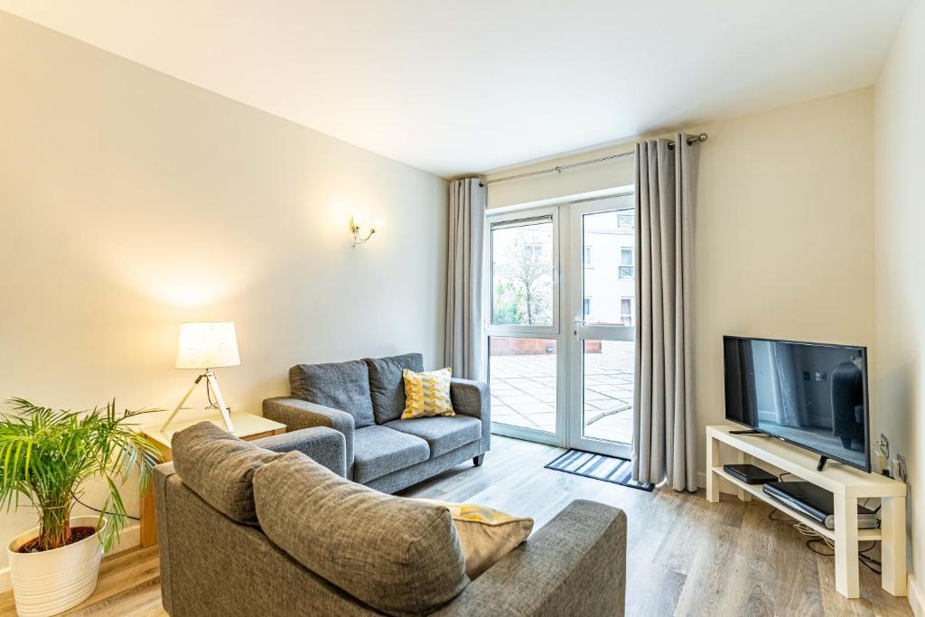 a living room with a couch and a tv at Cotels at Centro Serviced Apartments in Northampton