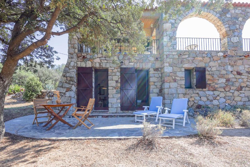 une table et des chaises à l'extérieur d'un bâtiment en pierre dans l'établissement Petite Pause de Fogata - Jolie vue mer, à Corbara