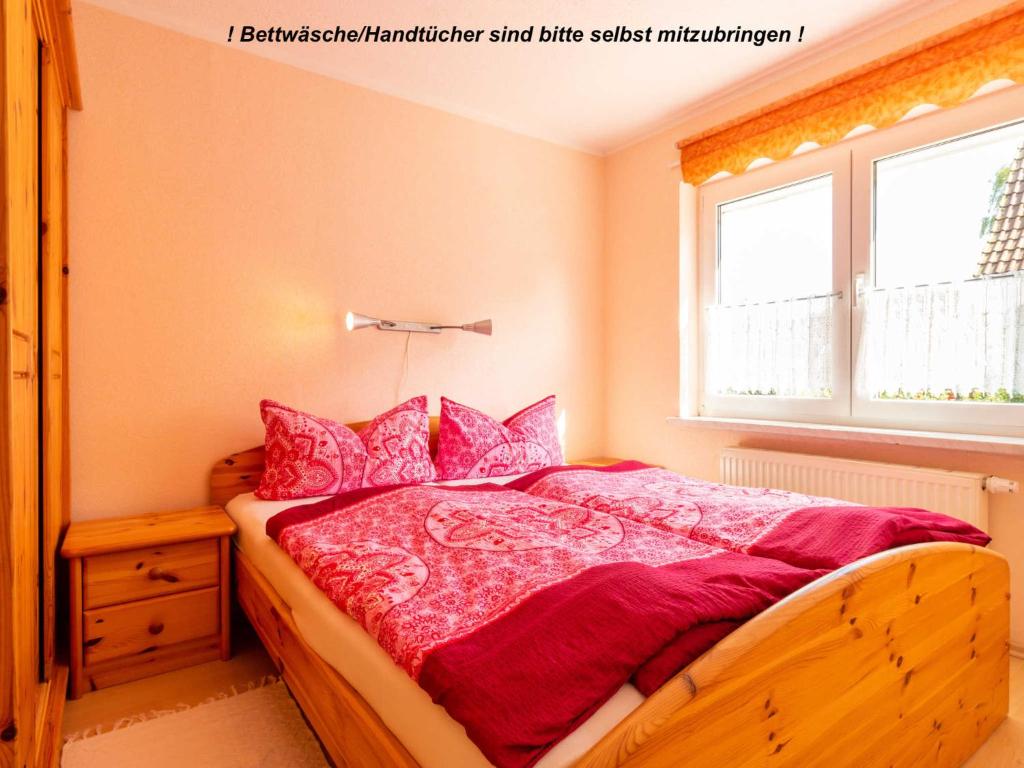 a bedroom with a bed with pink sheets and a window at Ferienwohnung Schwarz in Gademow