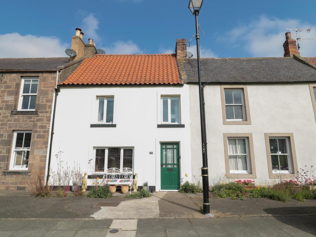 a white house with a bench in front of it at 2 Cross View in Berwick-Upon-Tweed