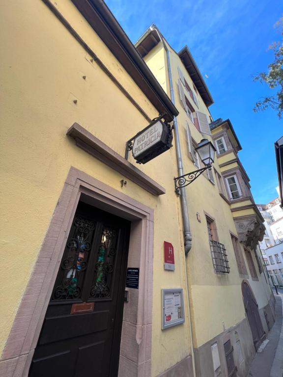 un bâtiment jaune avec une porte et un panneau au-dessus de celui-ci dans l'établissement Hôtel Patricia - Strasbourg Hyper Centre, à Strasbourg