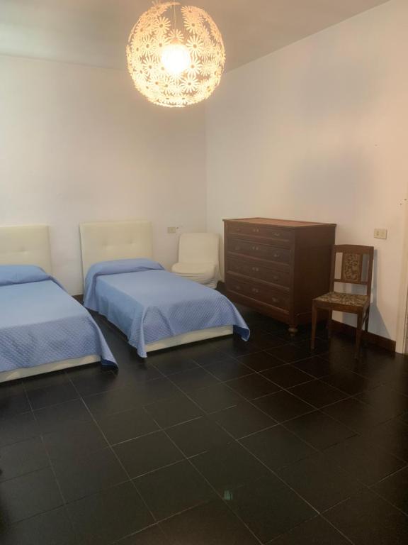 - une chambre avec deux lits, une commode et un lustre dans l'établissement Villa joy, à Calendasco