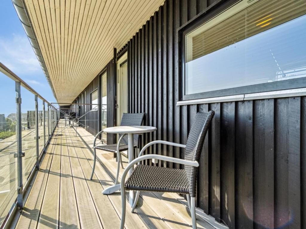 Apartment Kimi - 100m from the sea in Western Jutland by Interhome في Havneby: شرفة مع كرسيين وطاولة على مبنى