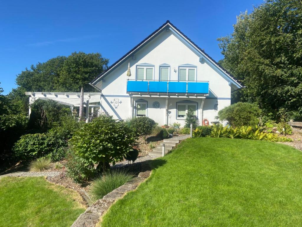 ein weißes Haus mit einem blauen Balkon und einem Hof in der Unterkunft Holiday Home Bellevue by Interhome in Bad Sachsa