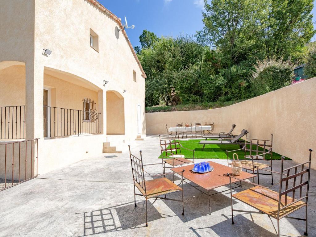 a patio with tables and chairs next to a wall at Holiday Home Malanuit by Interhome in Bauduen