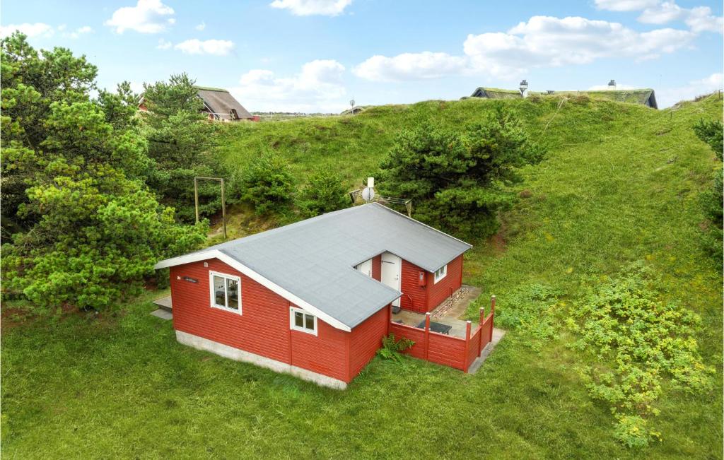 ein rotes Haus auf einem Grashügel in der Unterkunft Gorgeous Home In Fan With Kitchen in Fanø