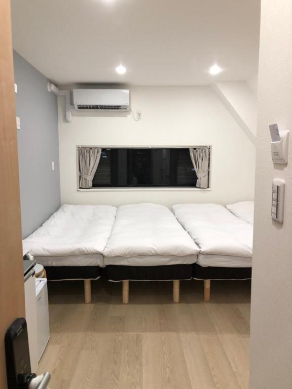 東京にあるOku Apartmentの窓の前にベッド2台が備わる客室です。