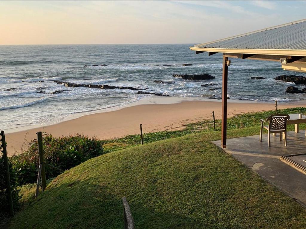 ein Tisch und ein Stuhl auf einer Veranda neben dem Meer in der Unterkunft Sea-Cottage Beachfront Accommodation in Sheffield Beach