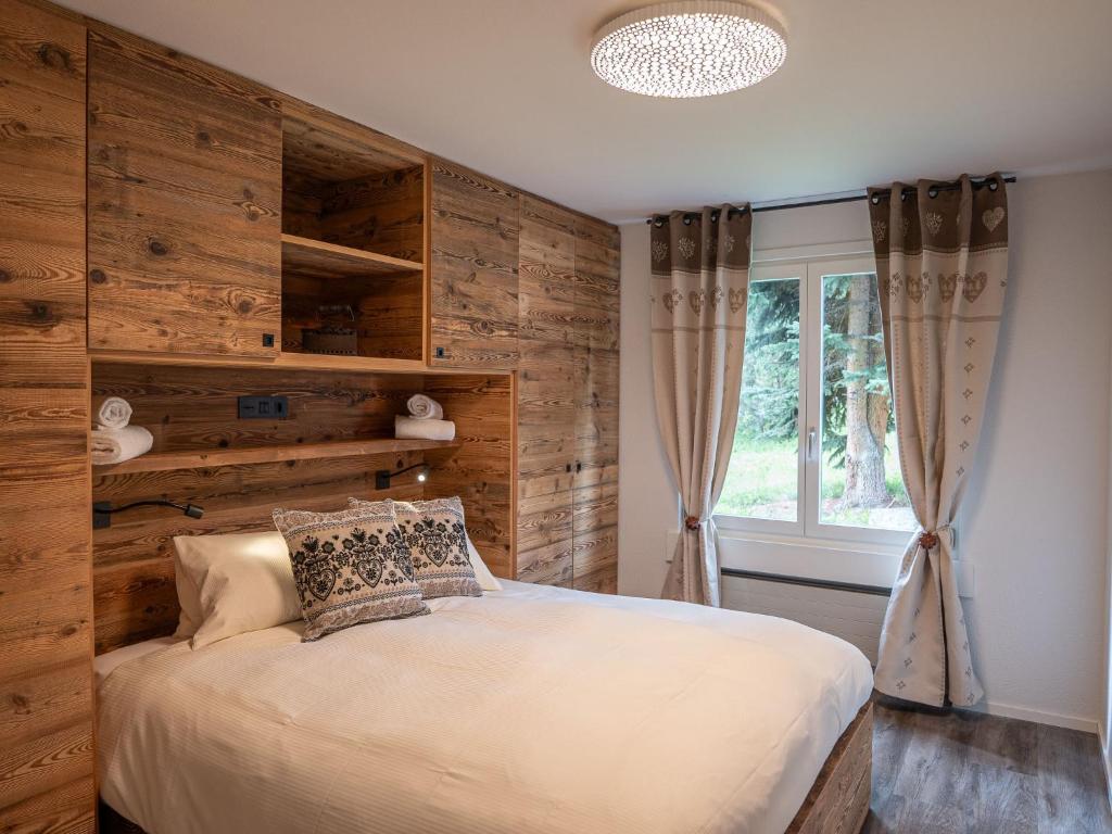 a bedroom with a bed with a wooden wall at Apartment Chesa Palüdin 10 - Pontresina by Interhome in Pontresina