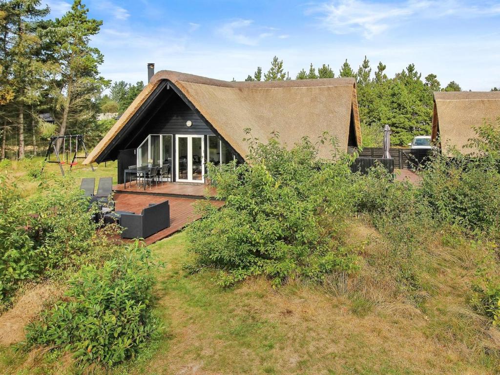 ein kleines Haus mit einem Strohdach auf einem Feld in der Unterkunft Holiday Home Awenasa - 4-1km from the sea in Western Jutland by Interhome in Nørre Nebel