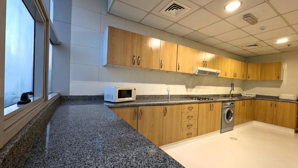 a large kitchen with wooden cabinets and a microwave at City Tower Hotel in Fujairah