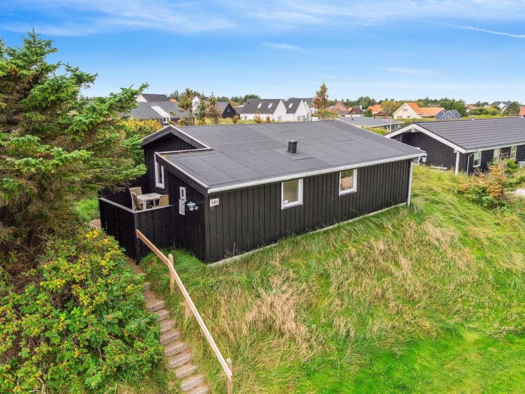 een zwart huis bovenop een grasheuvel bij Holiday Home Isabel - 500m from the sea in NW Jutland by Interhome in Torsted