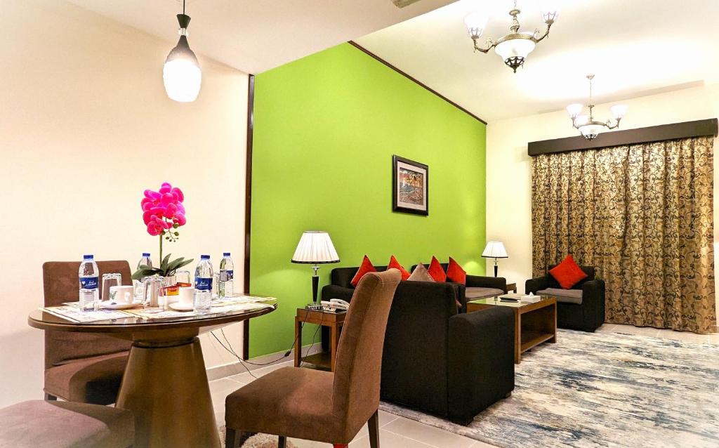 a living room with green walls and a table and a couch at City Tower Hotel in Fujairah