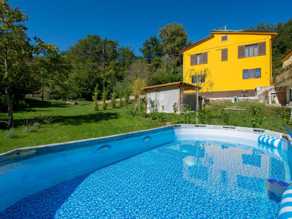 a pool in a yard with a yellow house in the background at Holiday Home Maya e Stella by Interhome in Bagni di Lucca