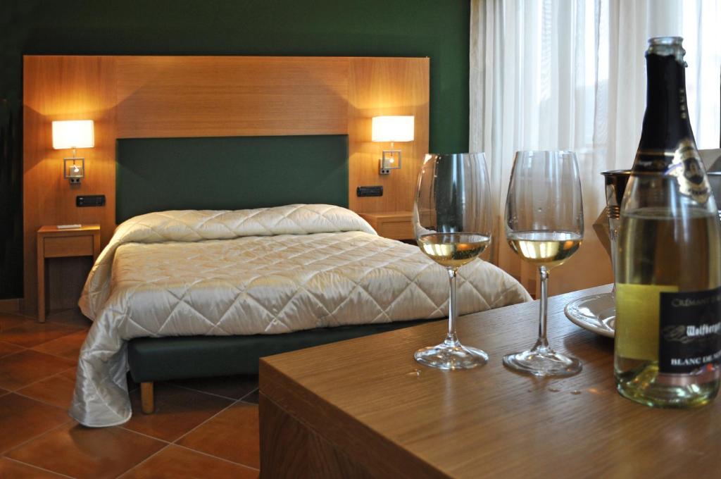 a bedroom with a bed and two glasses of wine at Mingone Hotel Ristorante in Isola del Liri