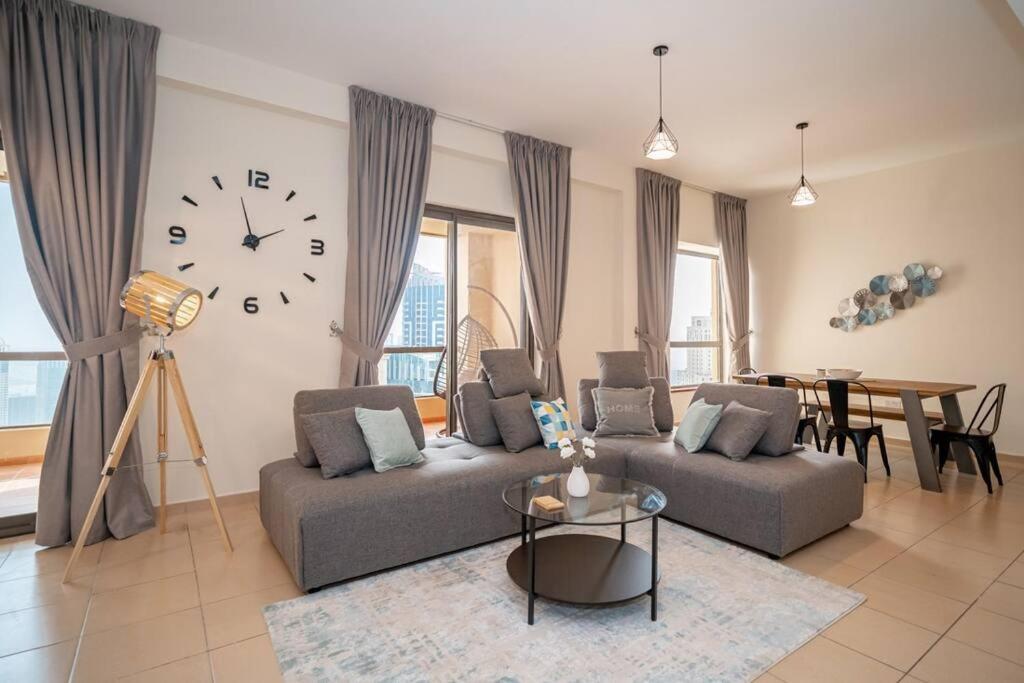 a living room with a couch and a clock on the wall at HiGuests - Fancy 1BR Apt With Aerial Marina Views in JBR in Dubai