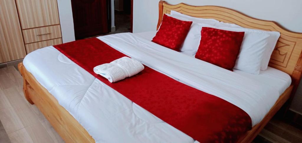 1 cama con sábanas rojas y blancas y almohadas rojas en GOLDEN PALM 3, en Nakuru
