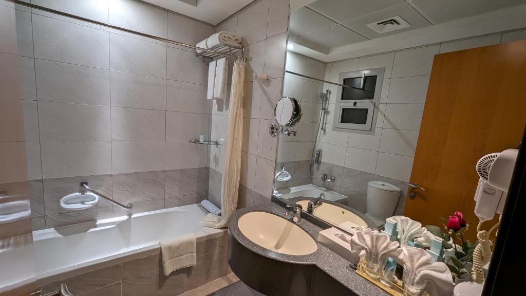 a bathroom with a tub and a sink and a bath tub at City Tower Hotel in Fujairah