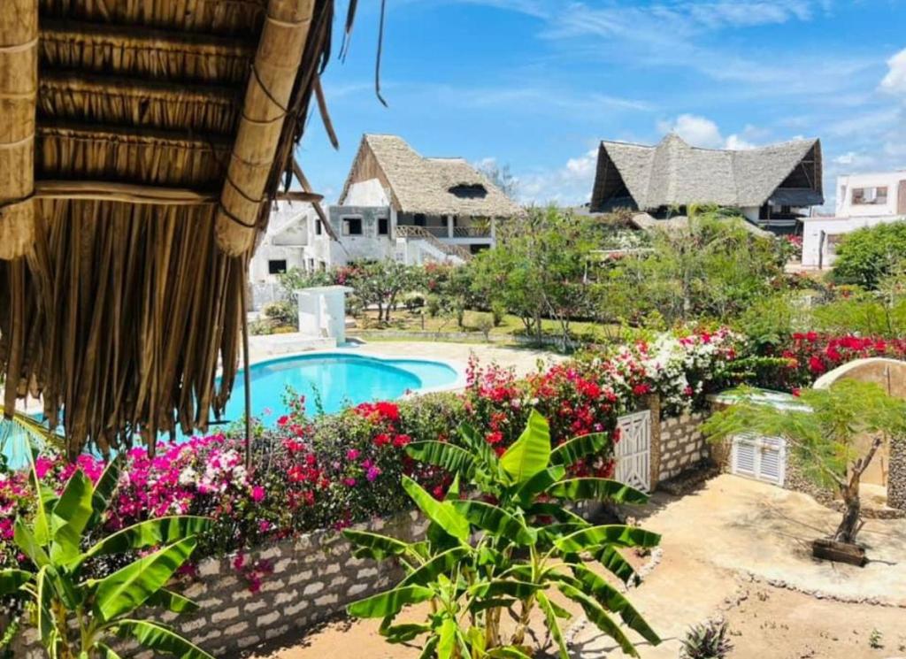 a resort with a swimming pool and flowers at Shira house in Watamu
