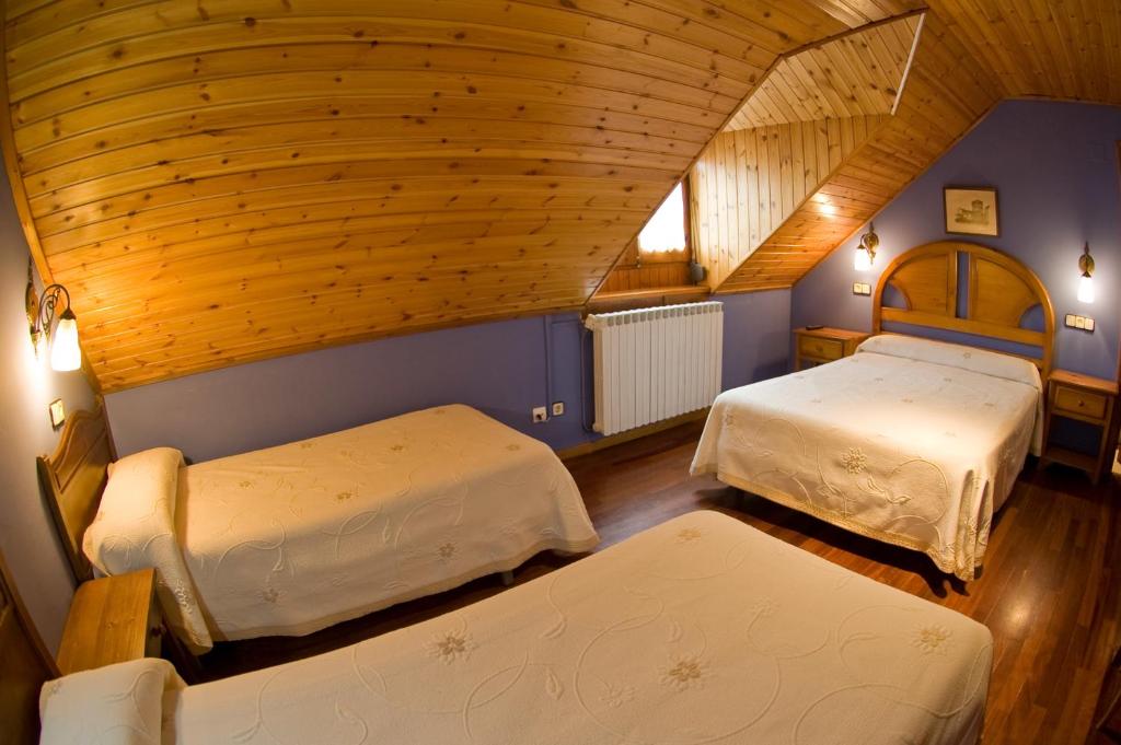 a bedroom with two beds and a wooden ceiling at Hotel Avenida Benasque in Benasque