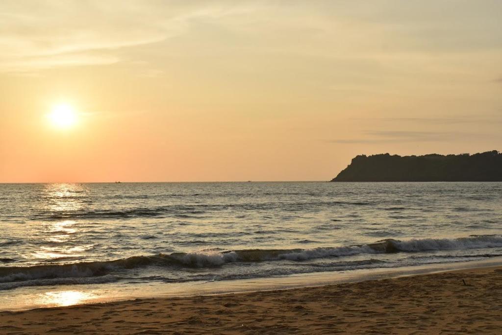 a beach with the sun setting over the ocean at Island Private Beach Retreat - Gokarna in Haldipur