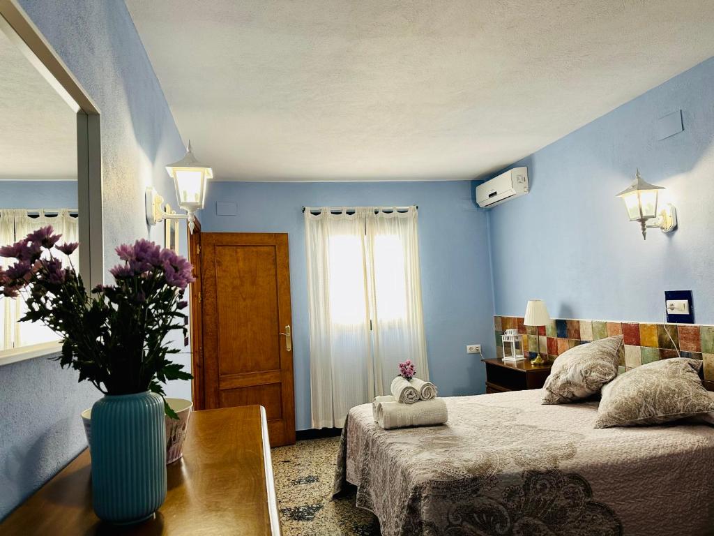 ein blaues Zimmer mit einem Bett und einer Vase mit lila Blumen in der Unterkunft Apartamentos Turísticos Santa Marina in Aracena