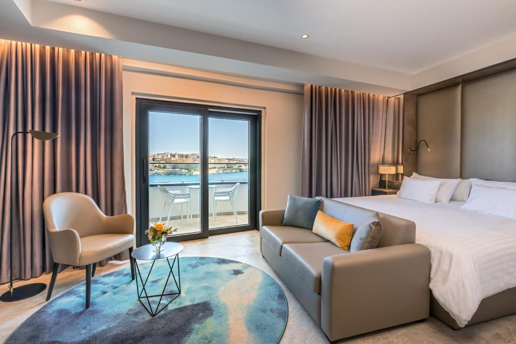 a bedroom with a bed and a couch and a window at Barceló Fortina Malta in Sliema