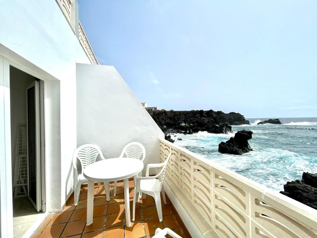 balcone con tavolo, sedie e vista sull'oceano di Oceanfront apartment a few meters from the beach a Tamaduste