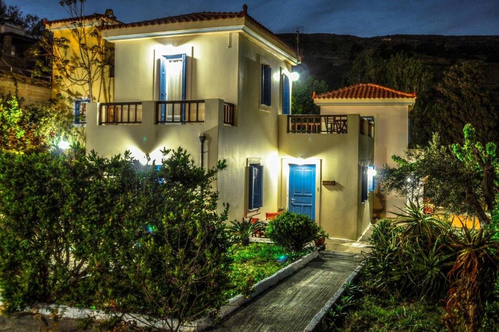 a white house with a blue door at night at Mainades Maisonettes & Studios in Ménites