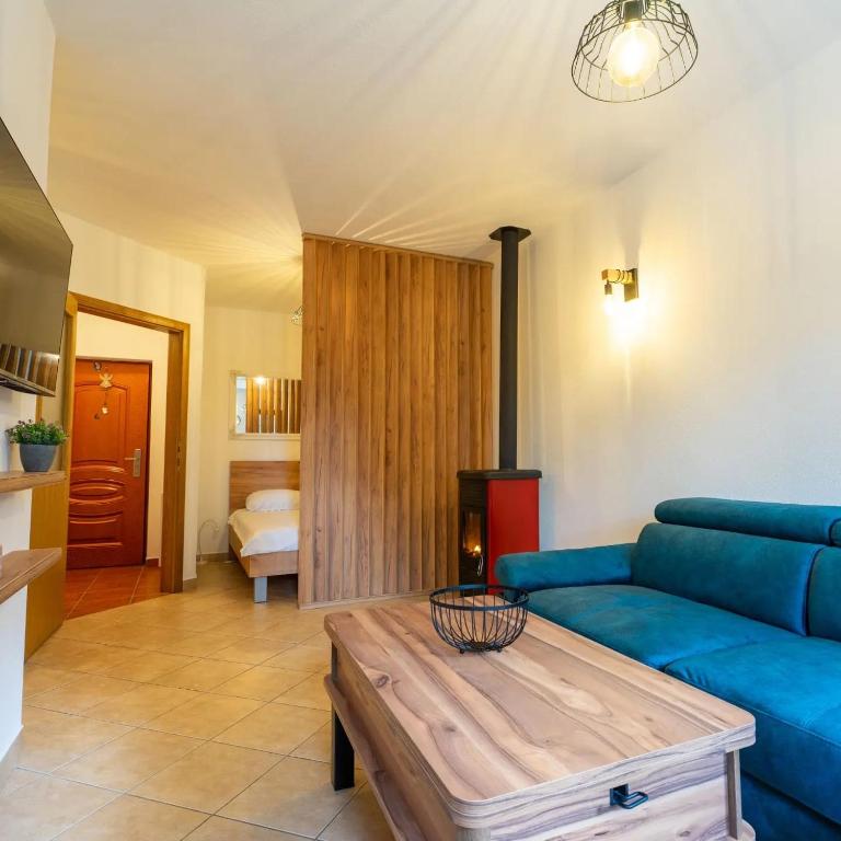 a living room with a blue couch and a table at Apartman Lux Blidinje Risovac in Blidinje