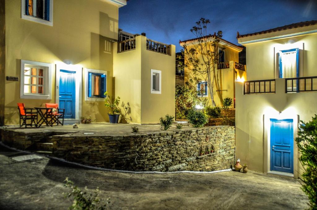 a house with blue doors and a stone wall at Mainades Maisonettes & Studios - Andros Serene Escape in Ménites