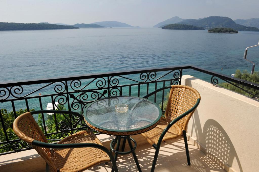 a table and chairs on a balcony overlooking the water at Logan's Beach Hotel in Nydri